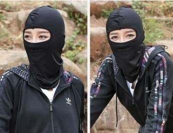 Woman riding a bike in the daytime at wearing black balaclava ski mask.